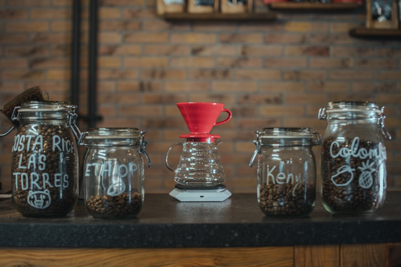A creative coffee brewing setup with jars labeled for different coffee origins, showcasing a vibrant cafe atmosphere.